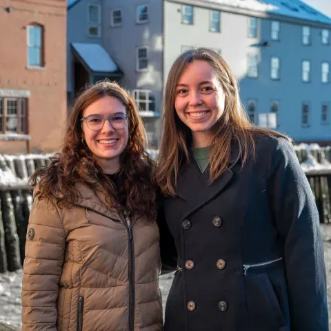 Two women pose in front of the Portland waterfront